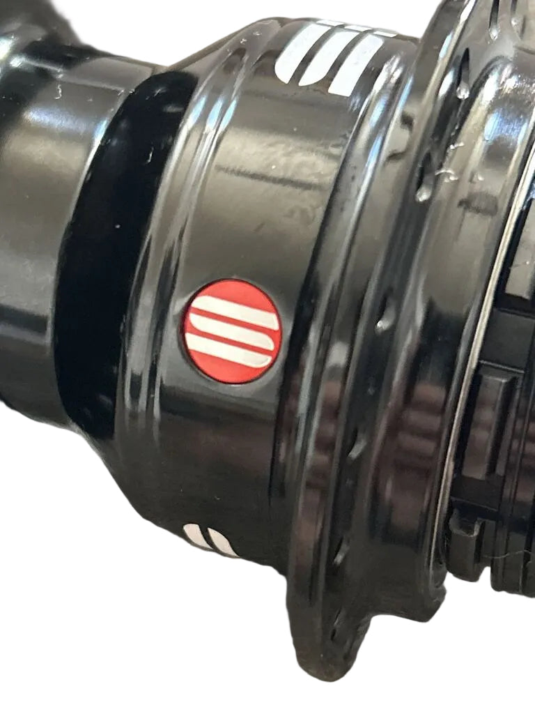 Close-up of a black bicycle wheel hub with a red and white circular logo sticker.